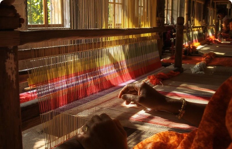 A weaver’s hands at a handloom in warm light