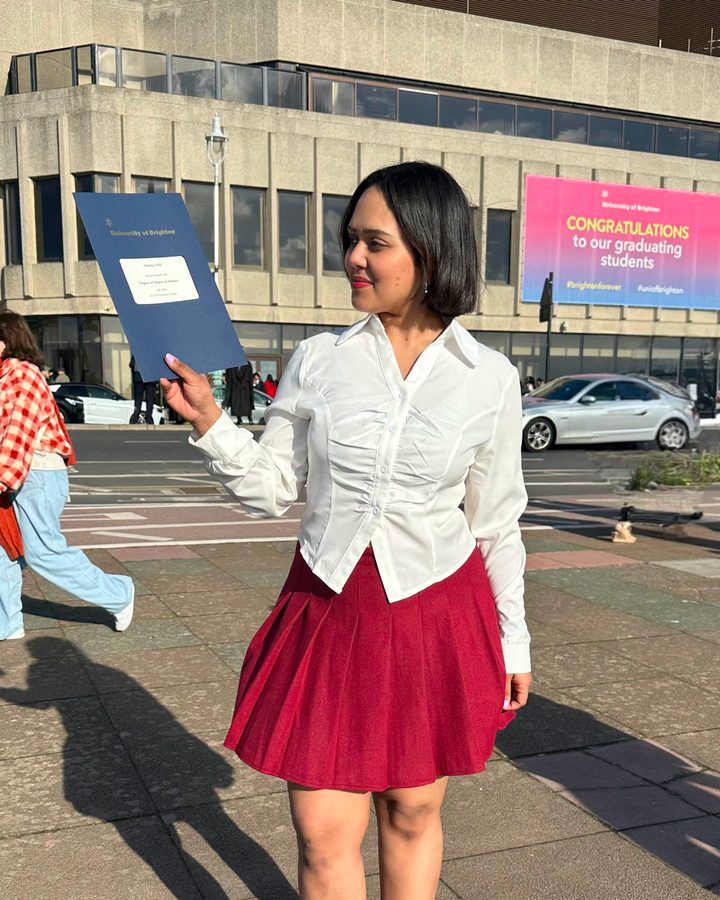 Anju holding her M.Sc. certificate outside the University of Brighton
